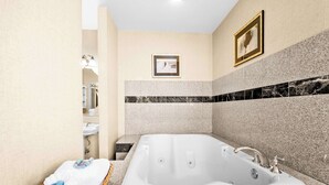 A modern bathroom with a large bathtub, a small sink, and a wicker basket with towels.