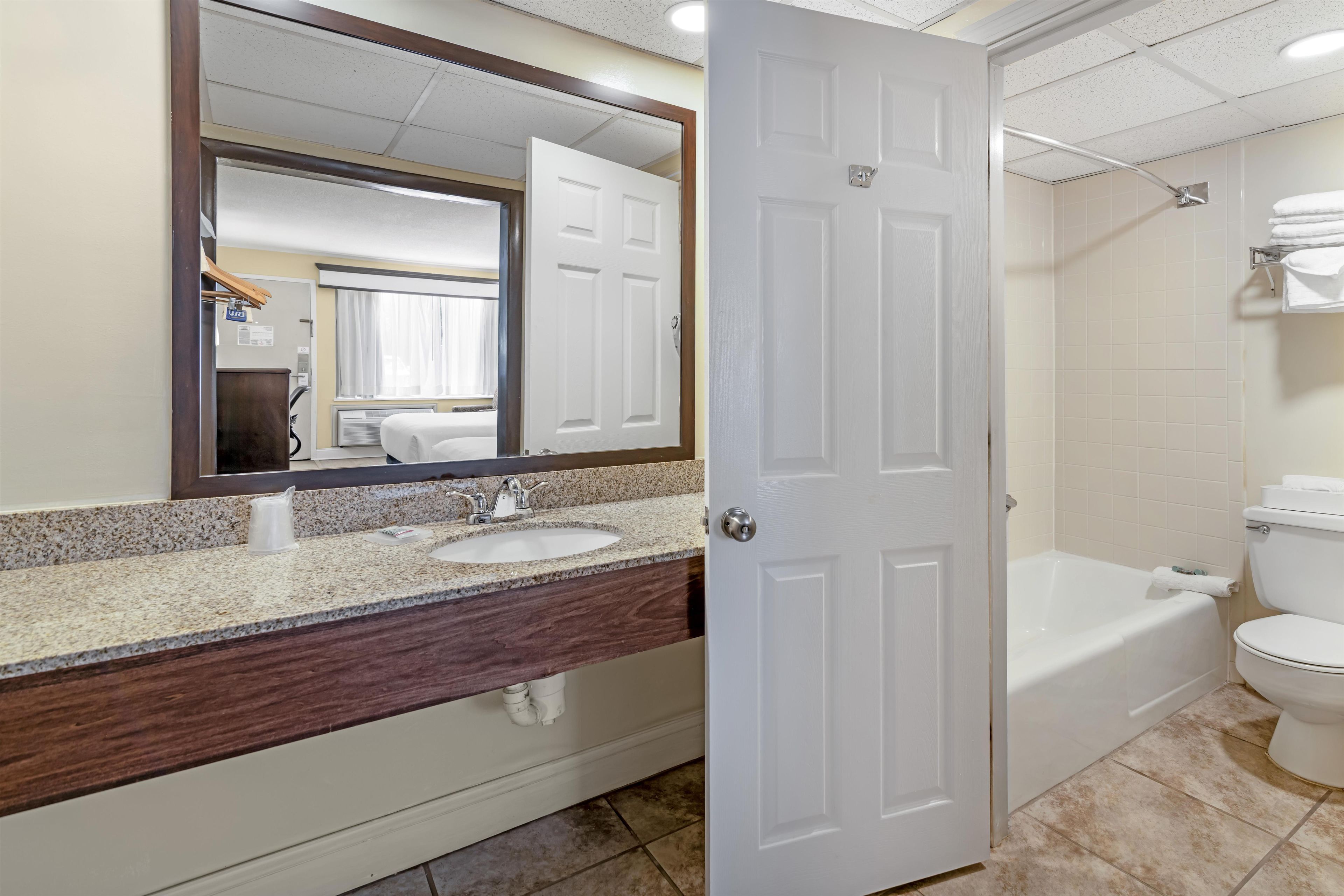 A bathroom with a white sink, mirror, and a door leading to a shower area.