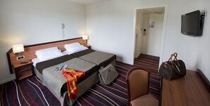 Relax in comfort with a neatly made bed, bedside table, and plush chair.