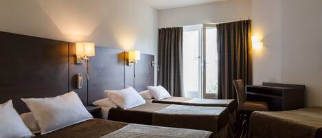 A hotel room with two beds, a desk, a chair, and a large window with curtains.