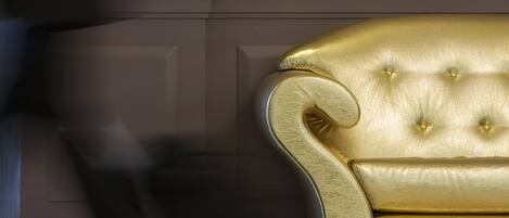 A room with a golden upholstered sofa, a wall-mounted light fixture, and a wooden panel wall.