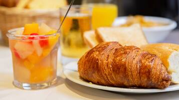 A breakfast setting with a croissant, fruit salad, toast, and orange juice.
