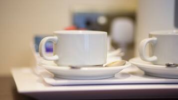 Two white cups on saucers with spoons, placed on a white tray.