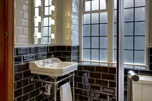 A bathroom with a white sink, black tiled walls, and a window with frosted glass. - Best Western Plough & Harrow Hotel (Birmingham)