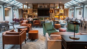 A spacious lobby with a large TV, comfortable seating, and a bar area. - Lea Marston Hotel (Sutton Coldfield)