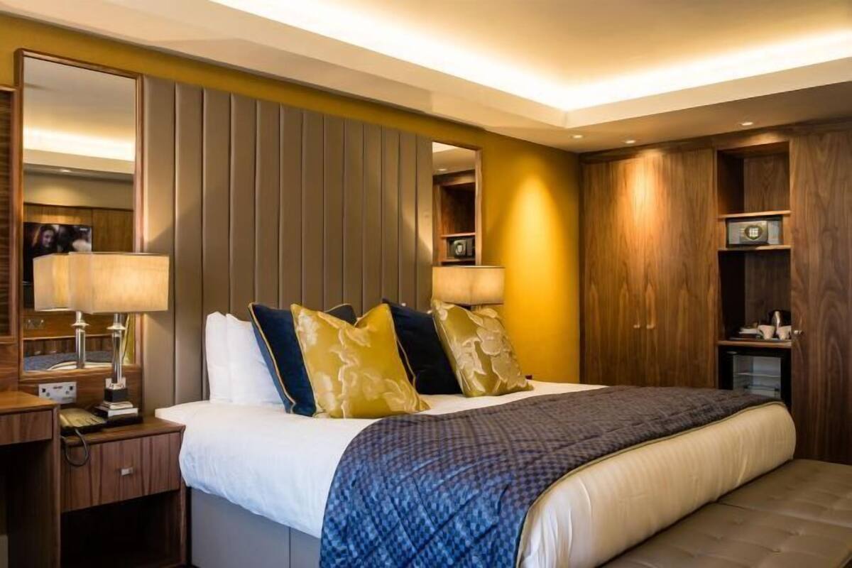 Une chambre d’hôtel avec un grand lit, des tables de chevet, un miroir et des rangements intégrés en bois.