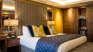 A hotel room with a large bed, bedside lamps, a wooden wardrobe, and a mirror. - Lea Marston Hotel (Sutton Coldfield)