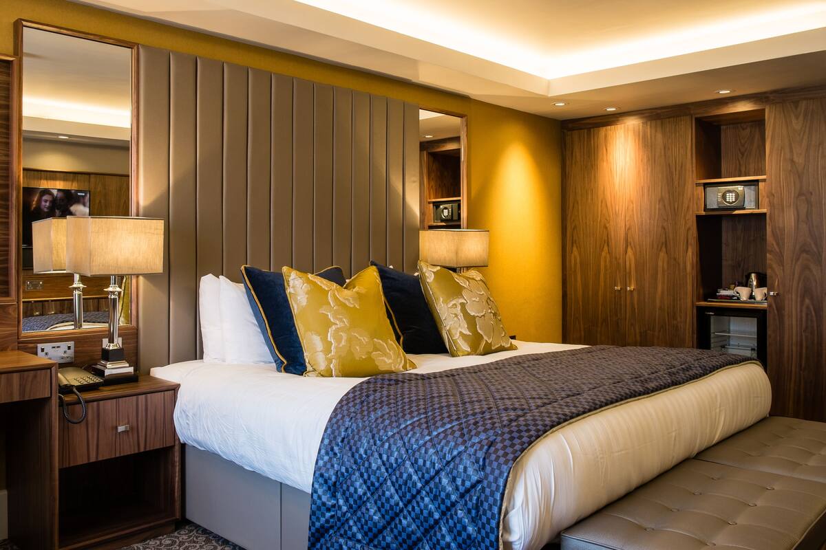 Une chambre d’hôtel avec un grand lit, des lampes de chevet, une armoire en bois et un miroir.