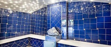 Een badkamer met blauwe betegelde wanden en een witte wastafel.