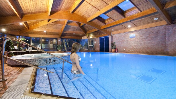 An indoor swimming pool with wooden beams, a tiled floor, and a glass barrier. - Lea Marston Hotel (Sutton Coldfield)