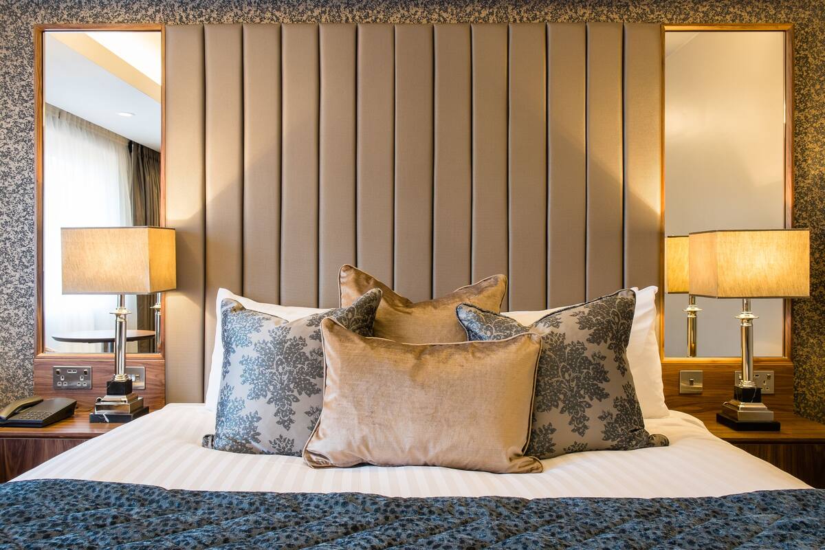 Une chambre d’hôtel avec un grand lit, deux lampes de chevet, une table de chevet et un miroir.