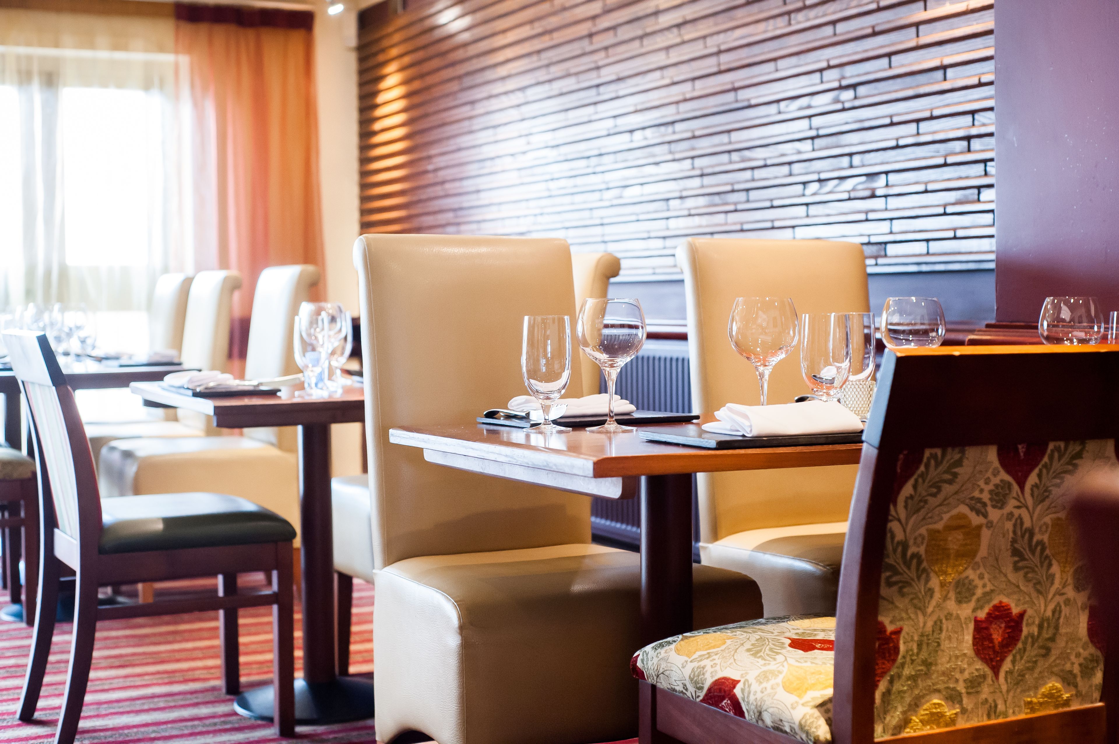 Un restaurante con sillas de cuero, mesas de madera y una pared de ladrillo.