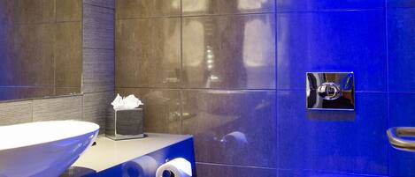 A modern bathroom with a large vessel sink, toilet, and a mirror above the sink.