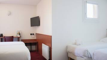 Ett hotellrum med två sängar, ett skrivbord, en stol, en tv och ett fönster.