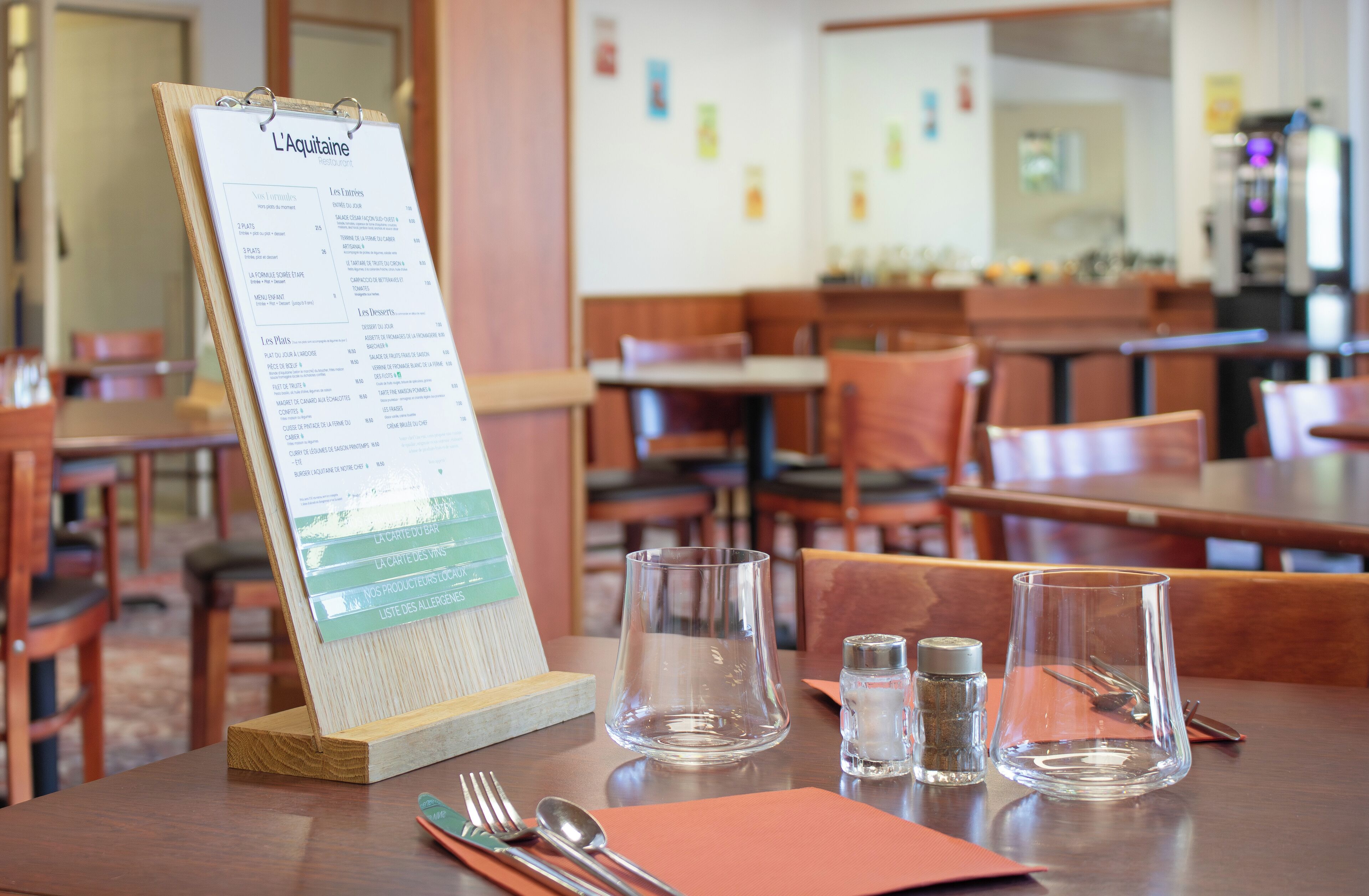 Un interior de restaurante con un atril para menús, mesas, sillas y vasos vacíos.
