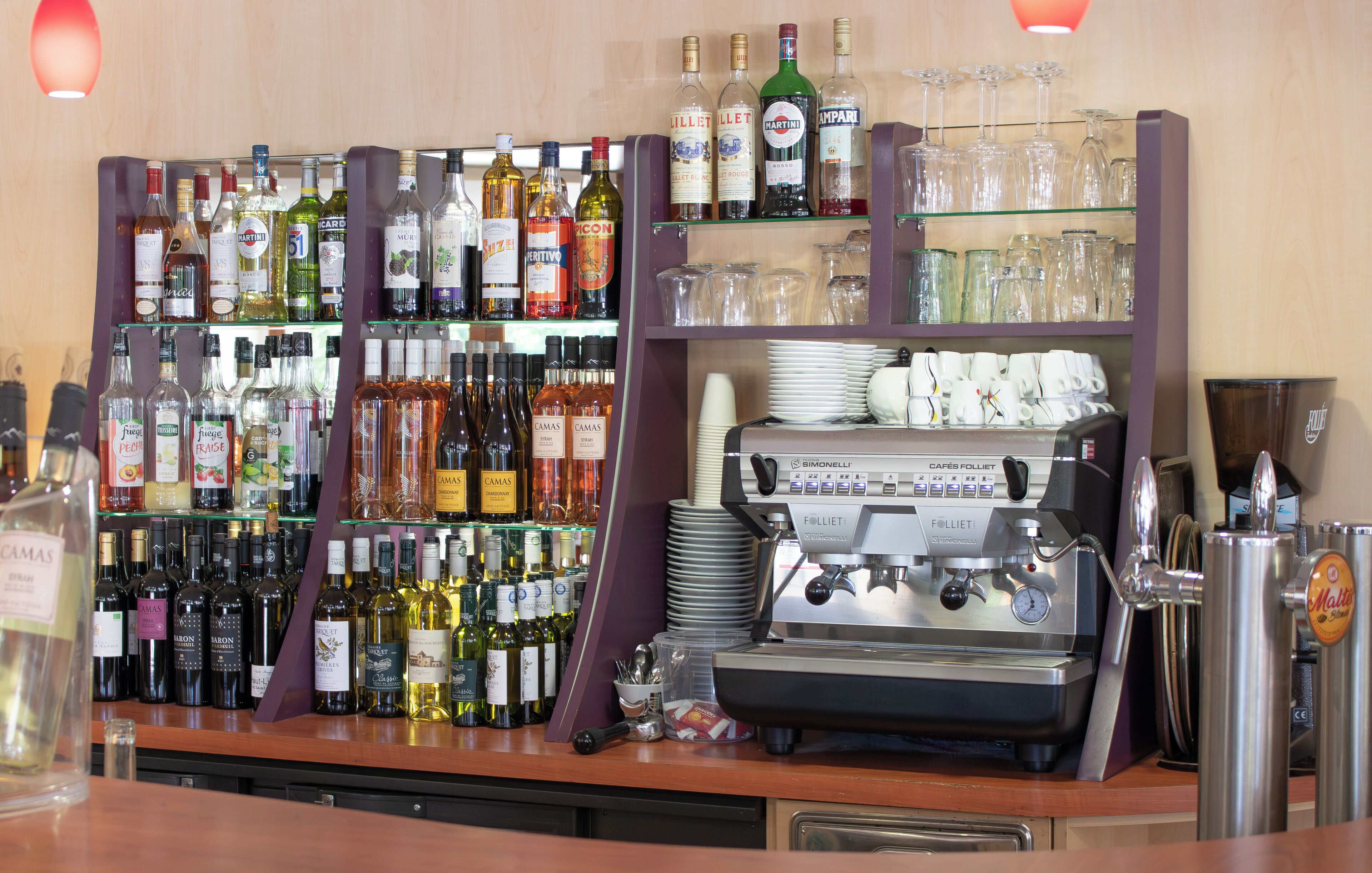 Zona de bar con una variedad de botellas de licor, vasos y una máquina de café.