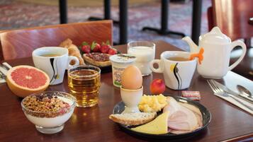 A breakfast tray with various foods and drinks, including a grapefruit, toast, cheese, ham, and a bowl of cereal.