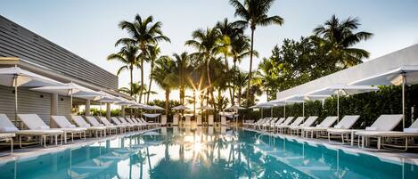 Una piscina al aire libre, camas de piscina con cargo, sombrillas