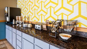A kitchen with a granite countertop, stainless steel appliances, and a yellow geometric wall pattern. - Days Inn by Wyndham Mt. Vernon (Mount Vernon)