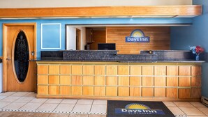A reception desk with a Days Inn logo, a wooden panel design, and a reception area with a door and a window. - Days Inn by Wyndham Mt. Vernon (Mount Vernon)