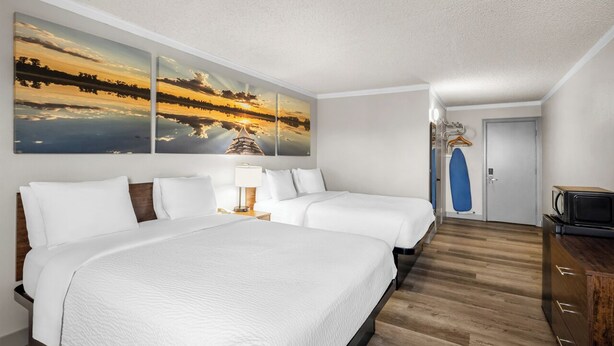 A hotel room with a large bed, two smaller beds, a TV, a microwave, and a door with a blue hanger. - Days Inn by Wyndham Mt. Vernon (Mount Vernon)