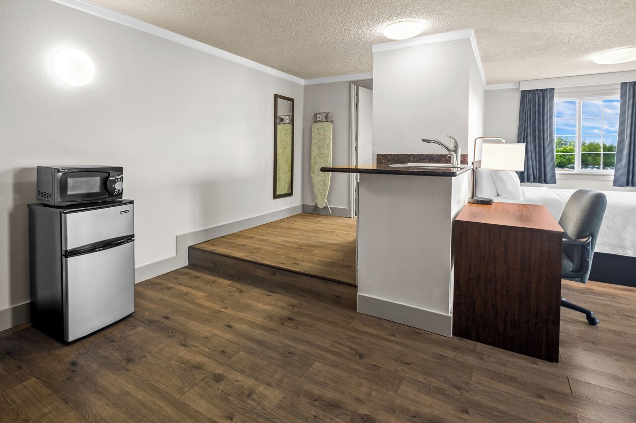 Habitación de hotel con kitchenette, escritorio, silla, cama y vistas al exterior.