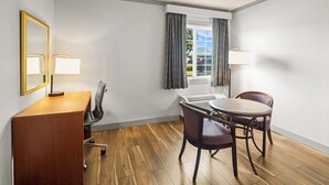 A hotel room with a wooden desk, two chairs, a round table, a window with curtains, and a mirror. - Days Inn by Wyndham Mt. Vernon (Mount Vernon)