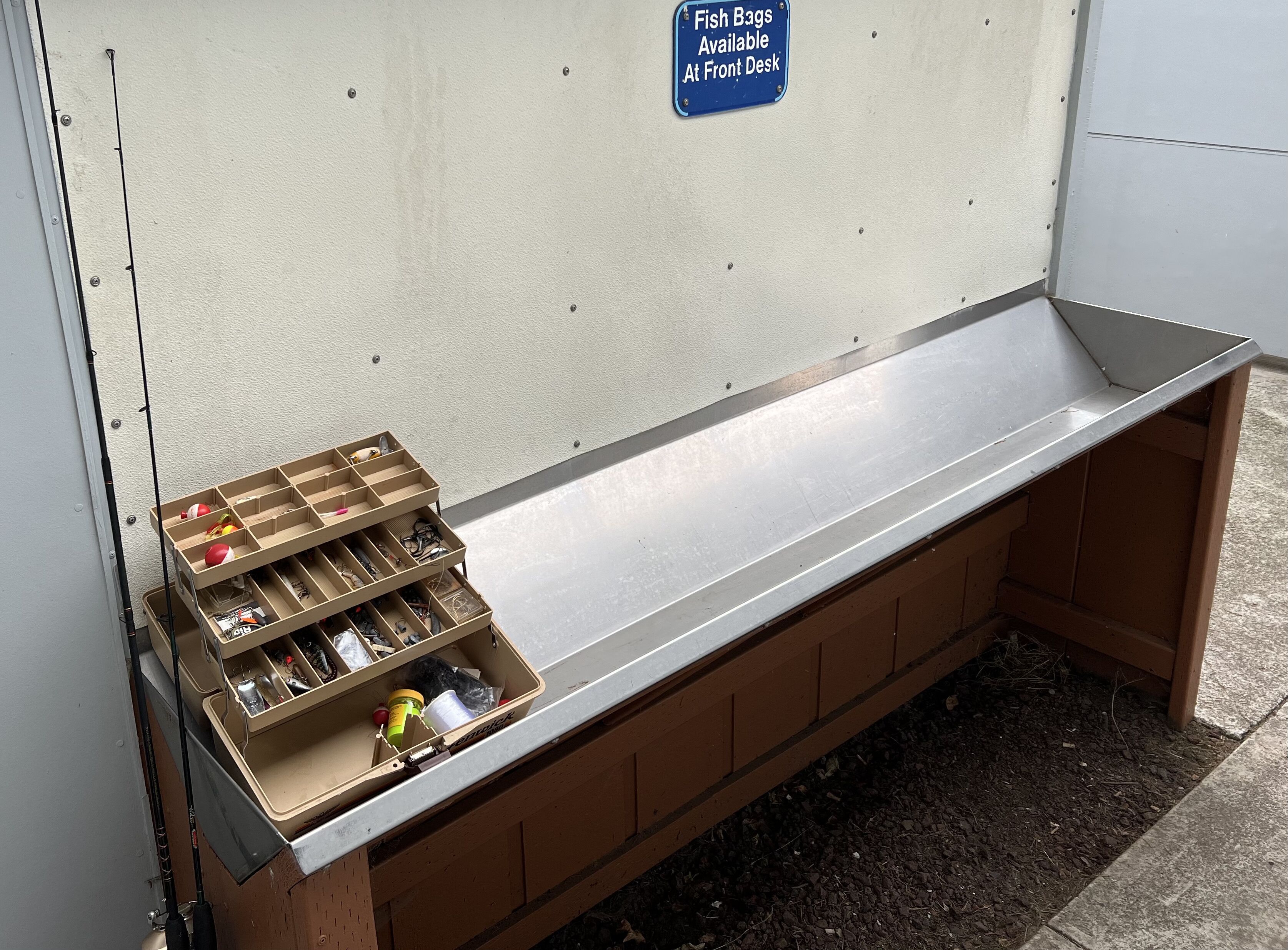 A storage bench with compartments containing fishing gear and a sign indicating fish bags are available at the front desk.