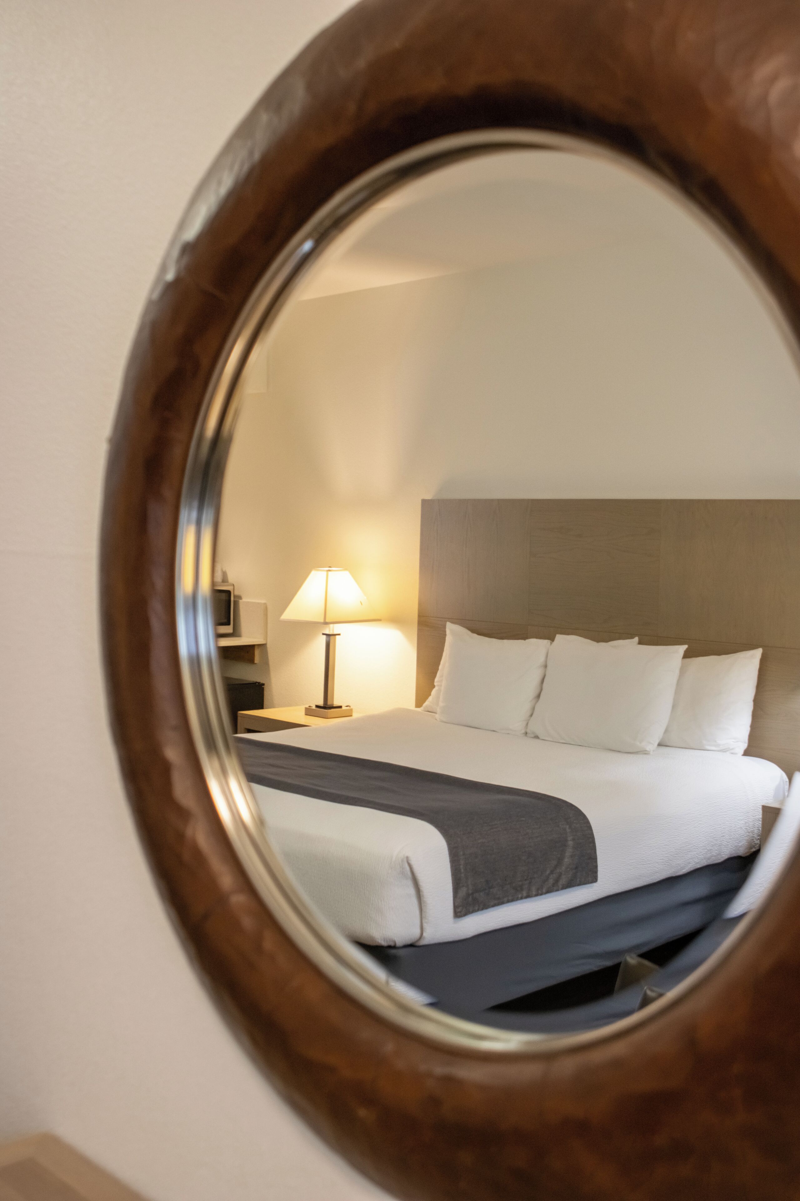 A hotel room with a bed, a bedside lamp, and a television on a stand.