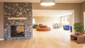 Un vaste espace de vie agrémenté d’une cheminée en pierre, de parquet et d’un mobilier contemporain.