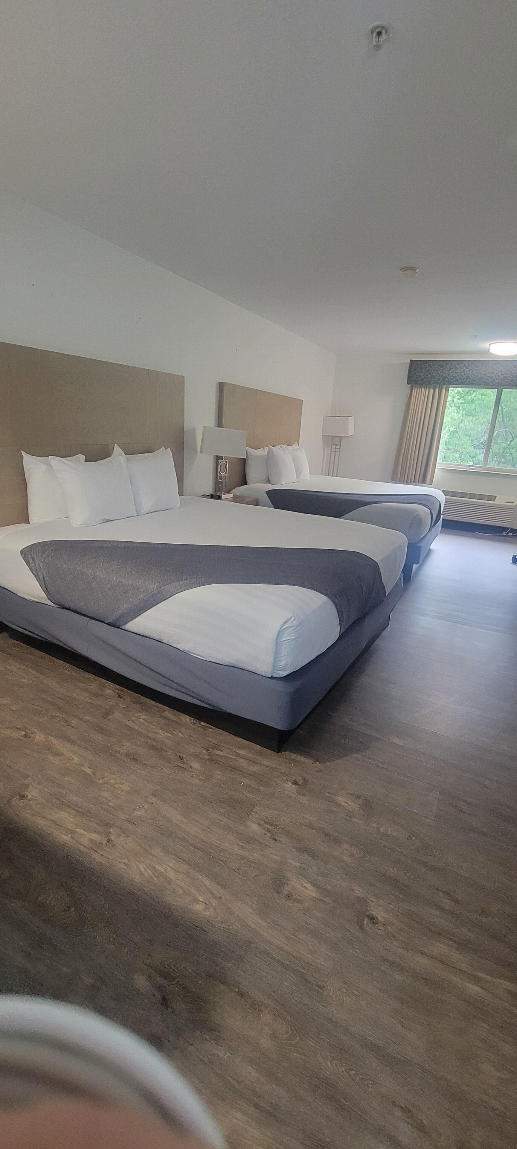 A hotel room with a large bed, two bedside tables, a lamp, and a window with curtains.