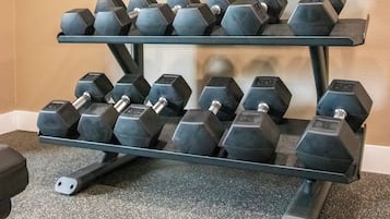 A three-tiered dumbbell rack with multiple weights.