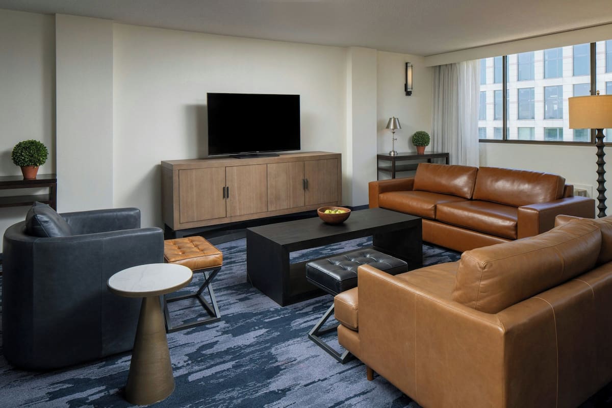 A modern living room with a television, leather sofas, a coffee table, and a patterned carpet.