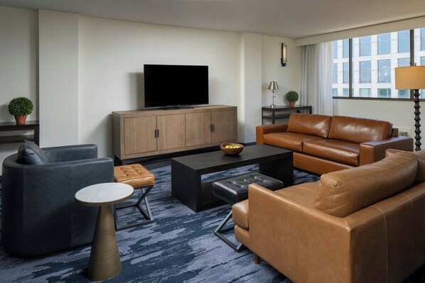 A modern living room with a television, leather sofas, a coffee table, and a patterned carpet. - Fairfield Inn & Suites by Marriott Charlotte Uptown (Charlotte)