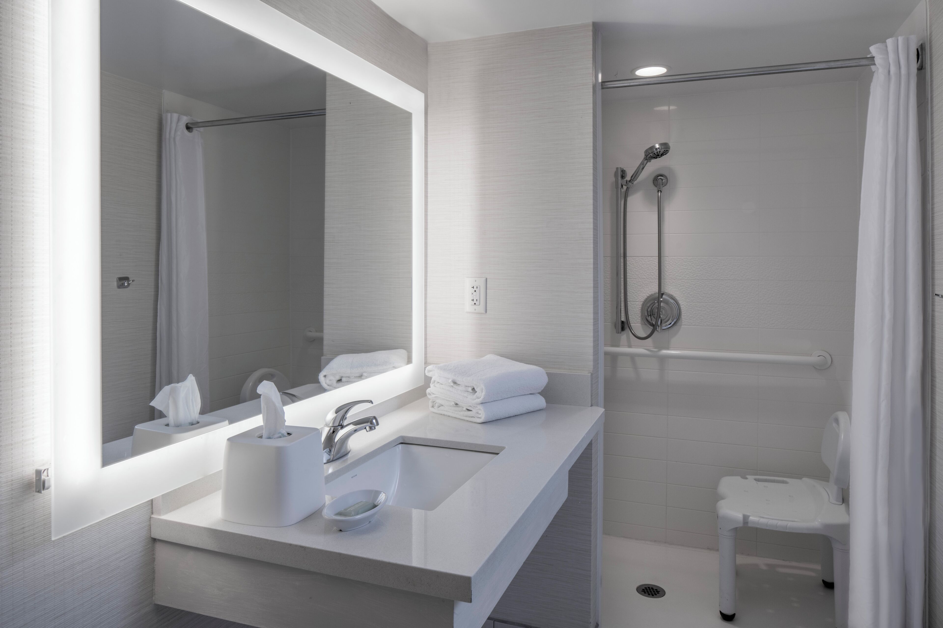 Une salle de bain moderne avec un grand miroir, deux lavabos, une douche et des toilettes.