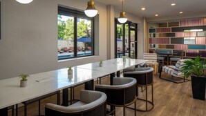A modern dining area with a long table, bar stools, and pendant lighting.