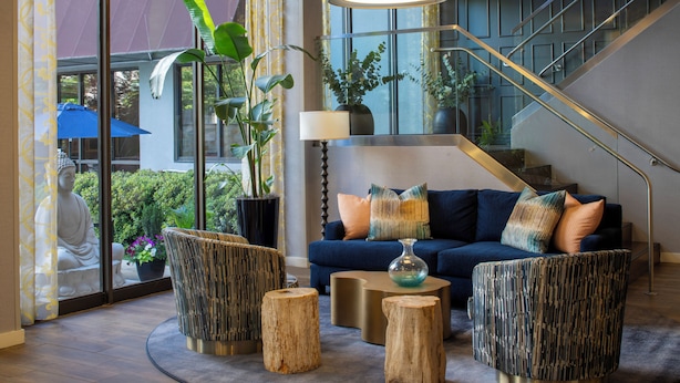 A modern living room with a blue sofa, round wooden tables, and a staircase.