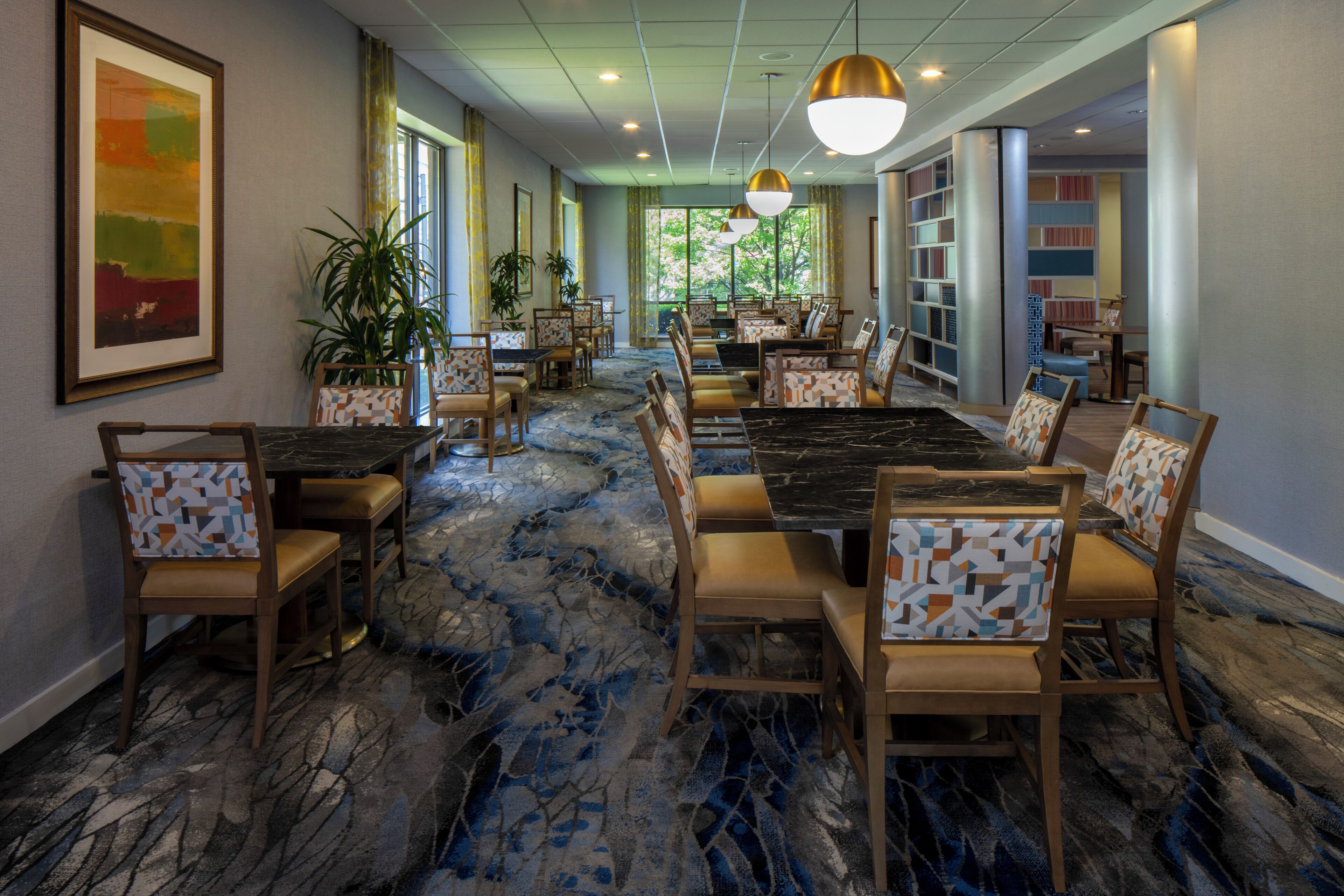 A hotel dining area with a long table, chairs, and a patterned carpet.