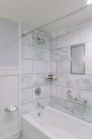 A modern bathroom with a bathtub, a shower, and a toilet.
