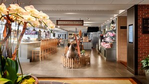 A restaurant with a wooden table centerpiece, orchid plants, and a sign for Henrietta's Table. - The Charles Hotel (Cambridge)