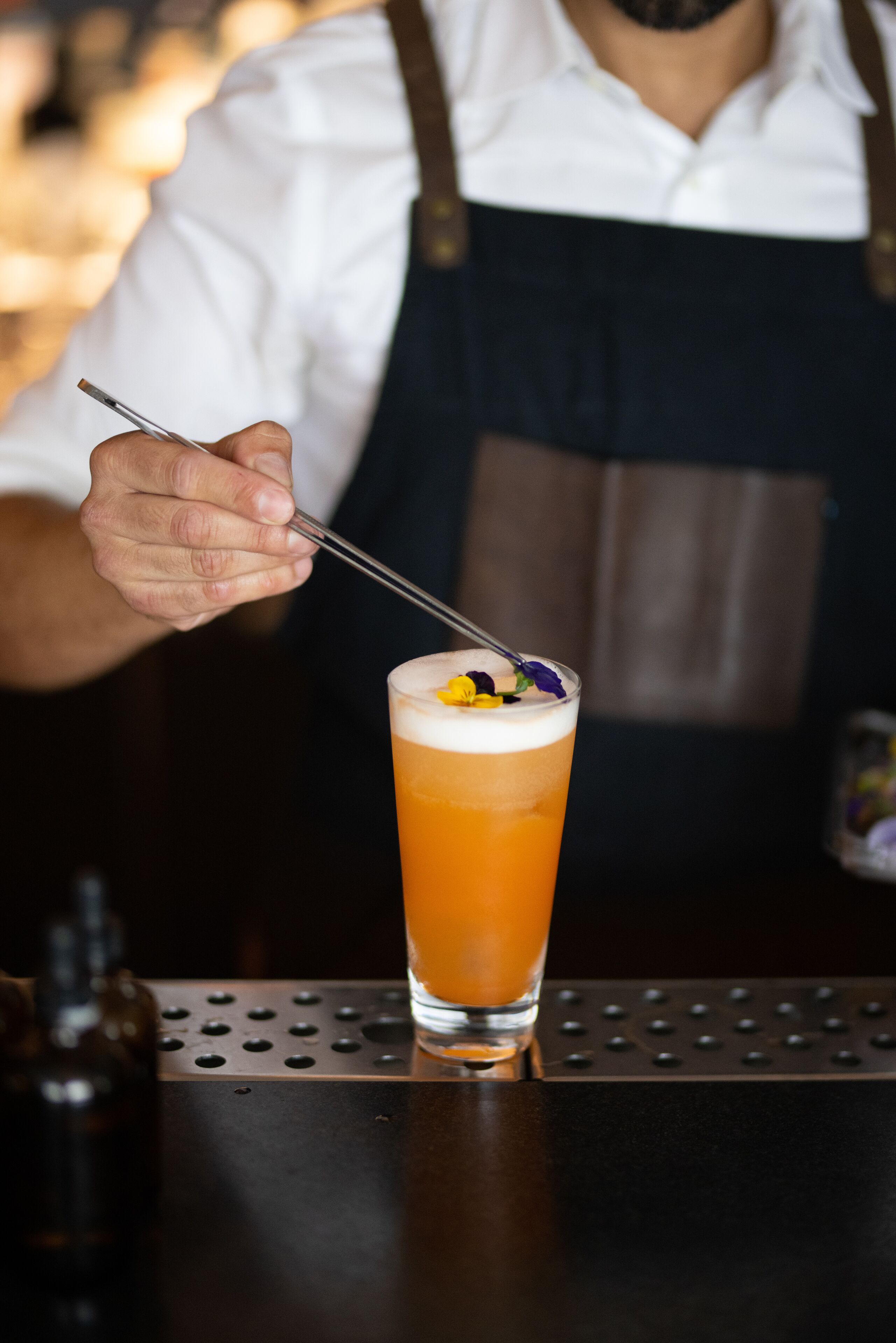 Un barman preparando una bebida con una cuchara.