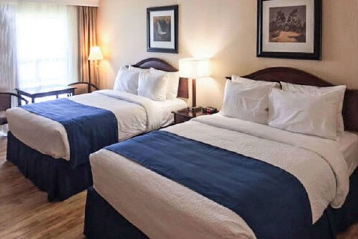 Ein Hotelzimmer mit zwei Betten, einem Schreibtisch und einem Stuhl.