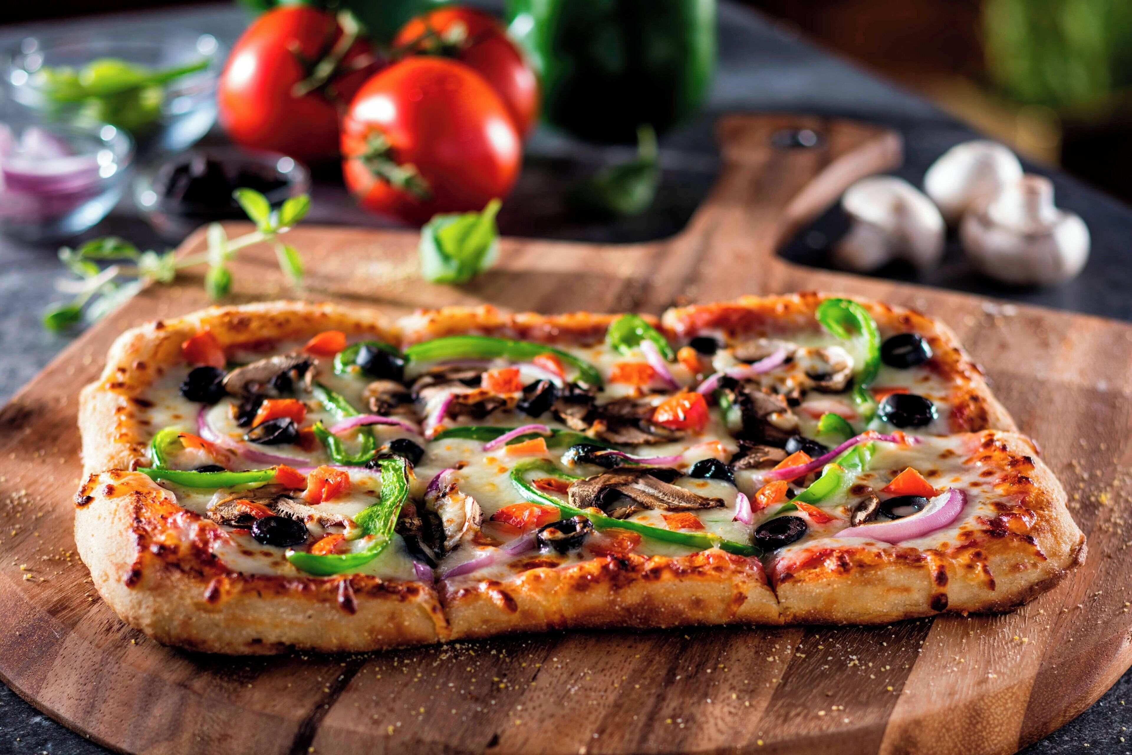 A pizza with various toppings on a wooden board.