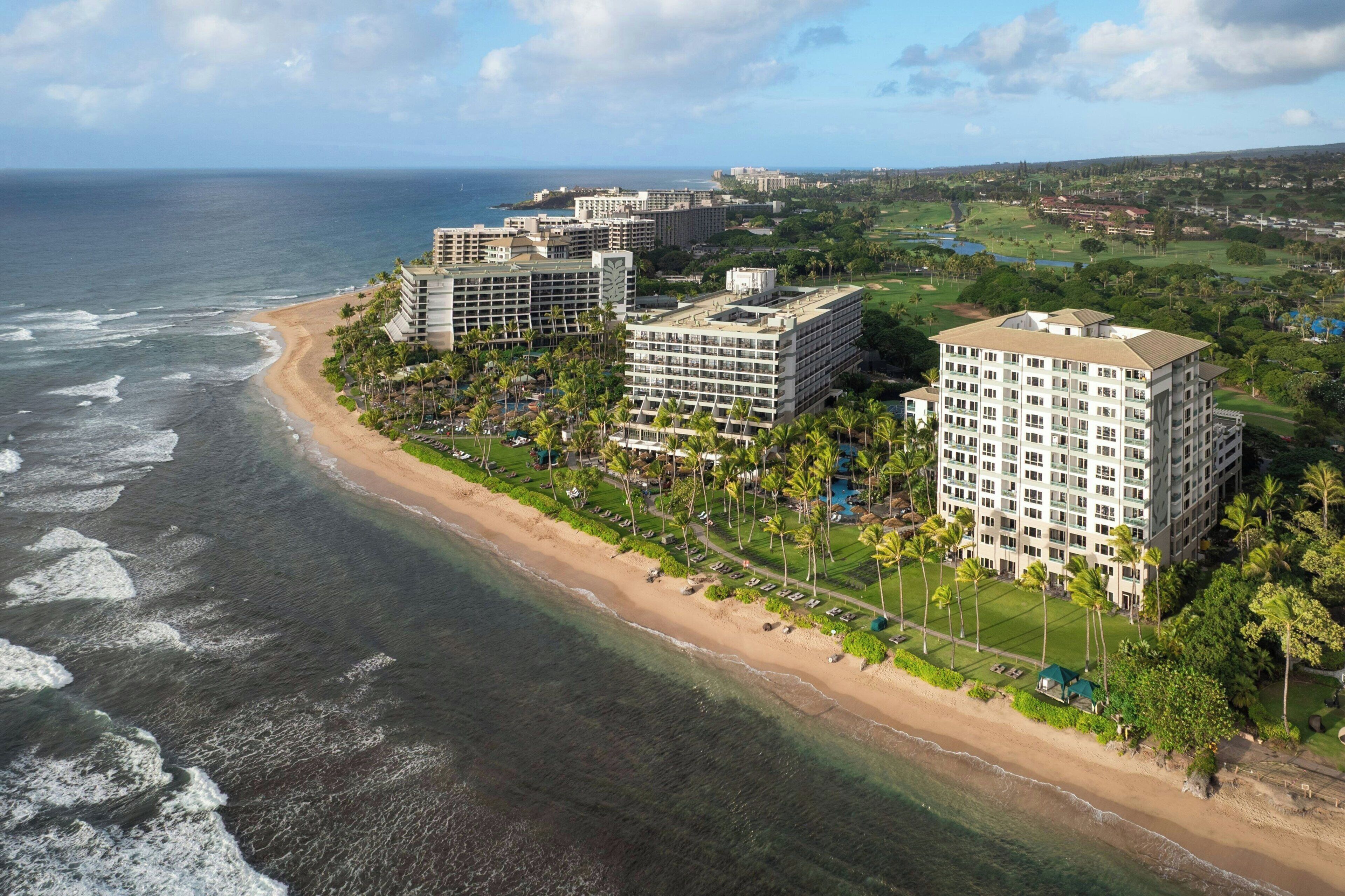 A coastal hotel with multiple buildings, a beach, and a golf course.