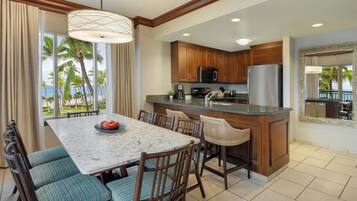 A kitchen with wooden cabinets, a stainless steel refrigerator, and a large island with a sink.