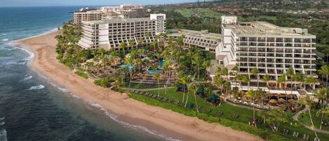 A beachfront hotel with multiple buildings, a pool area, and a beach.