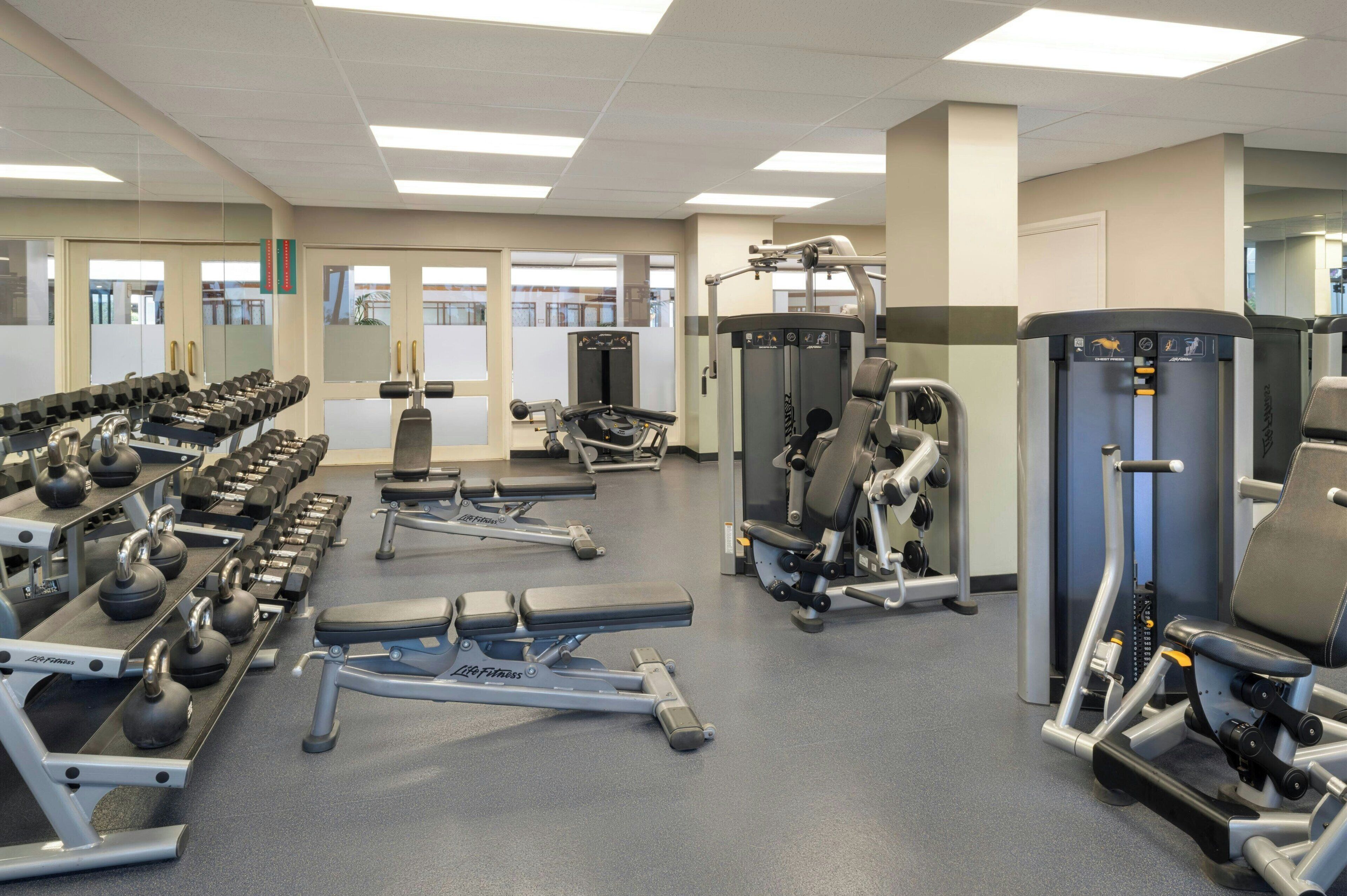 A gym with weight machines, dumbbells, and benches.
