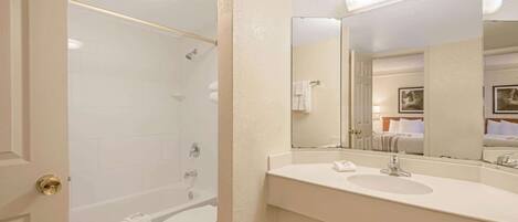 A bathroom with a bathtub, toilet, and a sink with a large mirror.