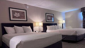 Two beds with white linens, a dark headboard, and a framed picture on the wall. - Ramada by Wyndham London (London)