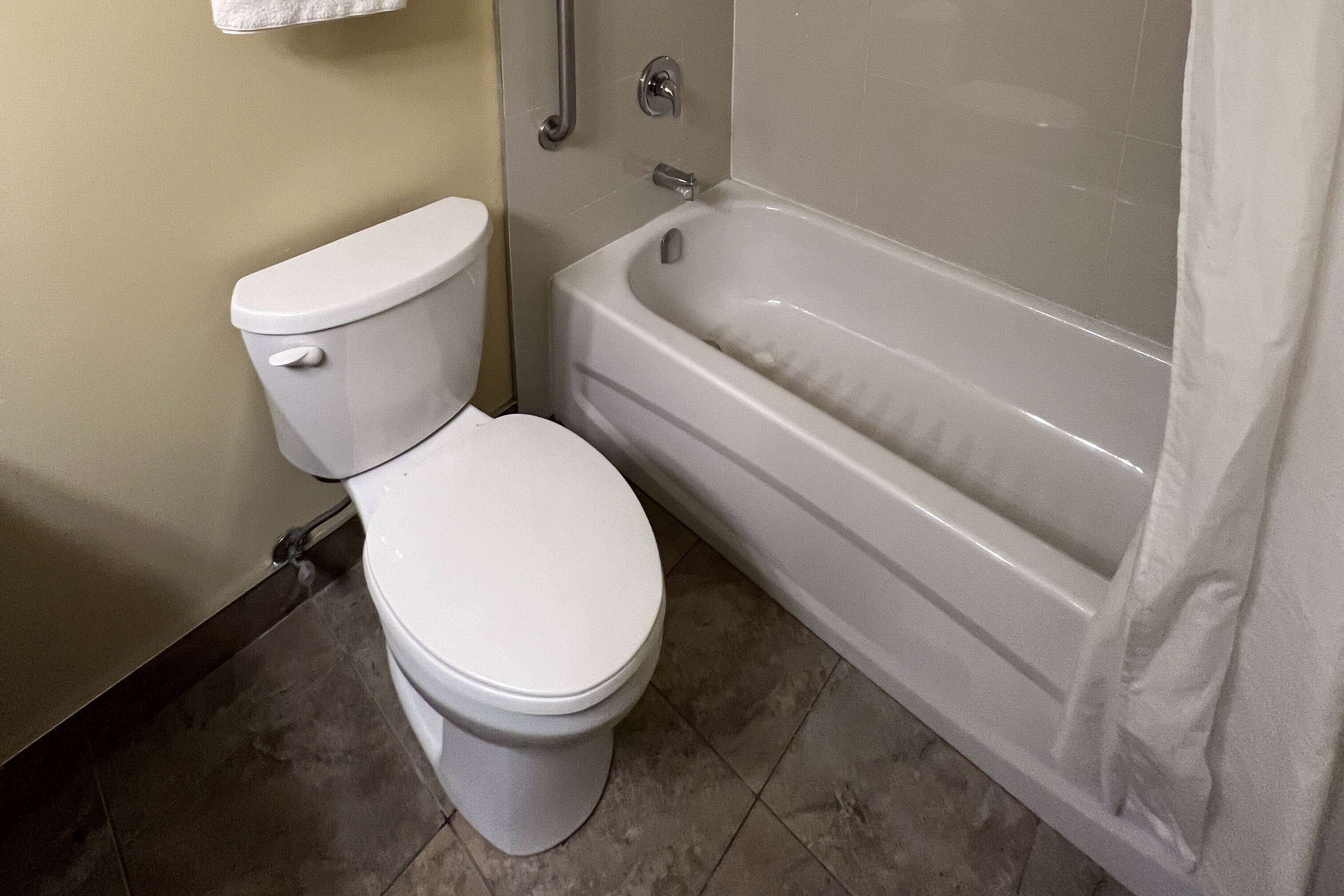 Un baño con inodoro, bañera y cortina de ducha.